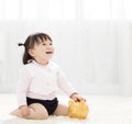 Baby girl inserting a coin into piggybank